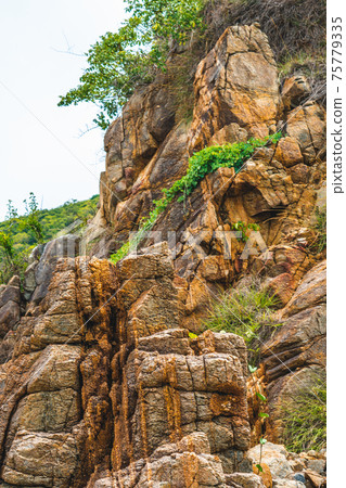 Close up view bright vivid orange brown yellow stone rock shabby cliff cracks texture mountains. Concept of geology, beauty power in nature. Natural summer composition landmark background design 75779335
