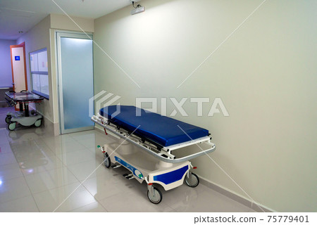 Patient bed on pathway in the hospital and wheelchairs 75779401