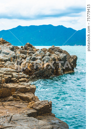 Beauty panorama pure blue lazure empty sea skyline, vivid brown gray rock shabby cliff, water splash, cumulus cloud sky, mountain island background. Concept sea tourism after pandemic, power in nature 75779415