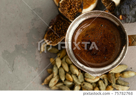 Copper coffee turk with dried seeds and fruits on grey surface 75782768