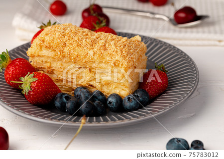 Piece of russian honey cake medovik served with berries 75783012