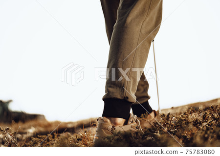 Man traveler with trekking sticks going up the mountain 75783080