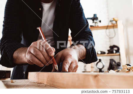 Carpenter makes pencil marks on a wood plank 75783113