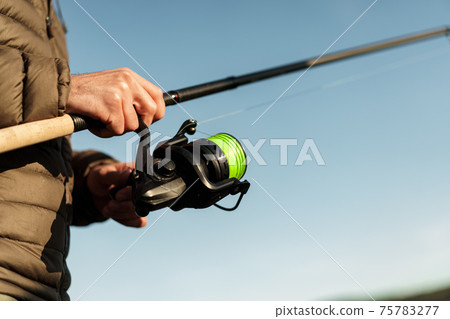 Fisherman hands holding fishing rod close up 75783277