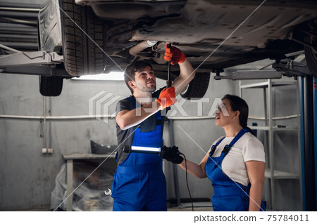 Techie and mechanic inspect car with torch 75784011