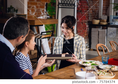 A celebration dinner, young family is exchanging presents 75784374