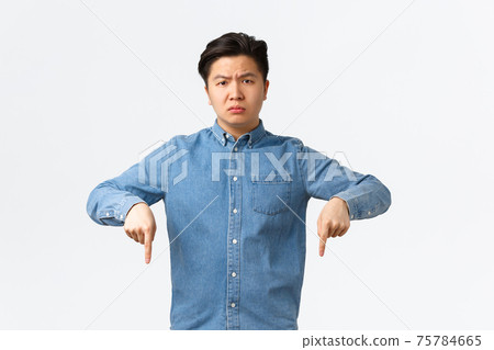 Disappointed and upset young asian guy complaining, looking concerned and displeased. Man in blue shirt pointing fingers down, making announcement, turn attention troubling news Disappointed and upset young asian guy complaining, looking concerned and displeased. Man in blue shirt pointing fingers down, making announcement, turn attention troubling news 75784665