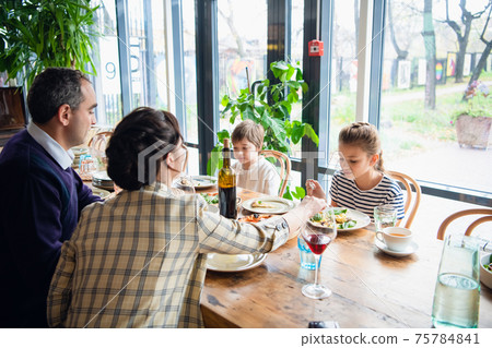 A family with kids in a cafe, the parents are drinking wine. A family with kids in a cafe, the parents are drinking wine. 75784841