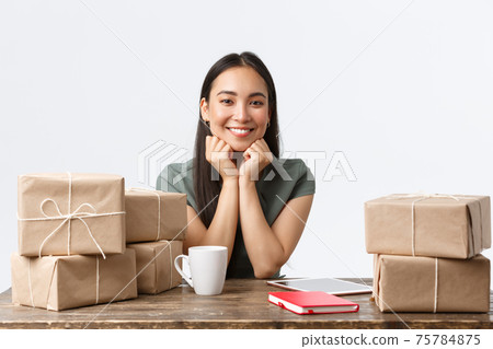 Small business owners, startup and e-commerce concept. Successful asian businesswoman working from home using digital tablet, selling products online shop, packing boxes with orders for shipping Small business owners, startup and e-commerce concept. Successful asian businesswoman working from home using digital tablet, selling products online shop, packing boxes with orders for shipping 75784875