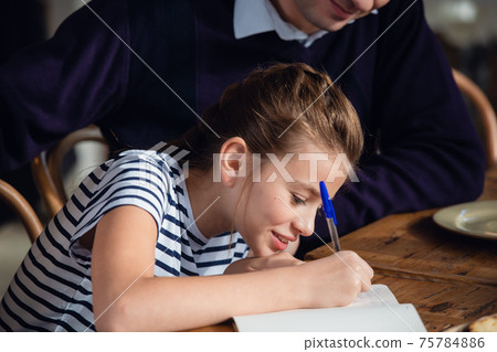 A girl writing something down in her notebook A girl writing something down in her notebook 75784886
