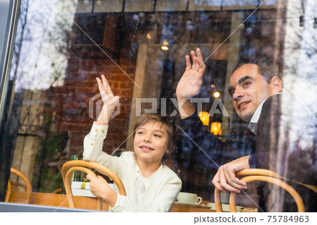 Beautiful father and son waving at someone Beautiful father and son waving at someone 75784963