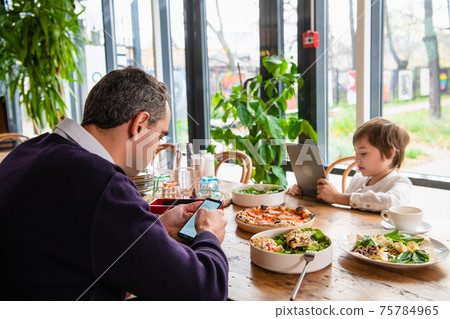 A boy playing on his tablet at the kitchen desk A boy playing on his tablet at the kitchen desk 75784965