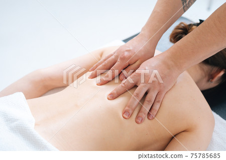 Top close-up view of male masseur massaging back and shoulders of female lying on massage table Top close-up view of male masseur massaging back and shoulders of female lying on massage table 75785685