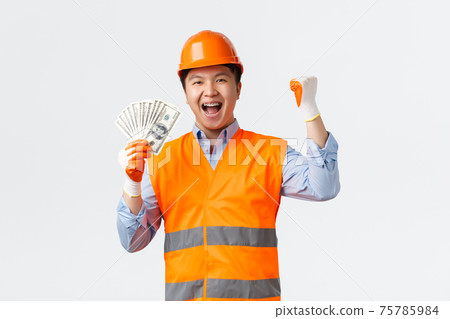 Building sector and industrial workers concept. Happy triumphing asian construction manager, architect in helmet and reflective clothing, fist pump saying yes and showing money, white background Building sector and industrial workers concept. Happy triumphing asian construction manager, architect in helmet and reflective clothing, fist pump saying yes and showing money, white background 75785984