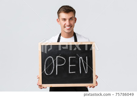 Small retail business owners, cafe and restaurant employees concept. Charismatic smiling waiter, salesman holding open sign, welcoming guests, standing white background Small retail business owners, cafe and restaurant employees concept. Charismatic smiling waiter, salesman holding open sign, welcoming guests, standing white background 75786049
