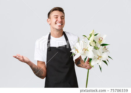 Small business, retail and employees concept. Charismatic happy salesman in flower shop, florist laughing delighted, made beautiful bouquet, proud of lilies, white background Small business, retail and employees concept. Charismatic happy salesman in flower shop, florist laughing delighted, made beautiful bouquet, proud of lilies, white background 75786339