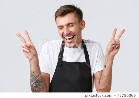 Cafe and restaurants, coffee shop owners and retail concept. Silly happy barista, salesman in black apron giggle funny and showing peace sign, glad finally open after covid-19, white background 75786869