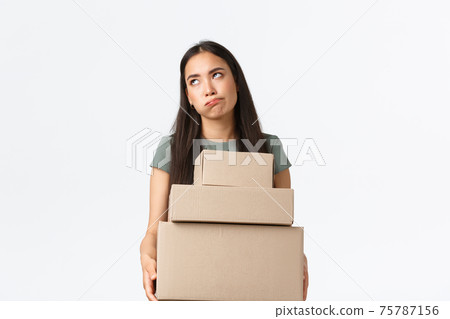 Small business owners, startup and work from home concept. Bothered asian female shop manager, store director carry heavy boxes to delivery company shipping orders to customers, white background Small business owners, startup and work from home concept. Bothered asian female shop manager, store director carry heavy boxes to delivery company shipping orders to customers, white background 75787156