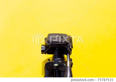 Camera tripod on yellow background. Camera tripod on yellow background. 75787515