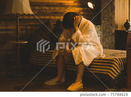 A man in a bathrobe sitting on the bed 75788828
