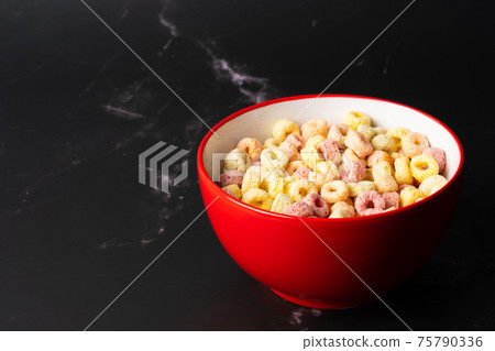 Cereal flakes in red bowl with copy space,Breakfast concept.Food with delicious fruity taste and fruity colours.It's made with maize,wheat,and barley. Cereal flakes in red bowl and dark backdrop. 75790336