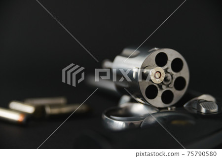 357 magnum caliber revolver pistol, cylinder open with a single bullet protruding from the gun 75790580