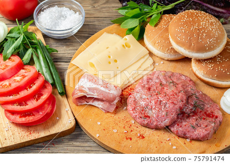 Process of cooking homemade burgers, meatballs, tomatoes, cheese and other ingredients on a wooden table, flat lay, top view 75791474