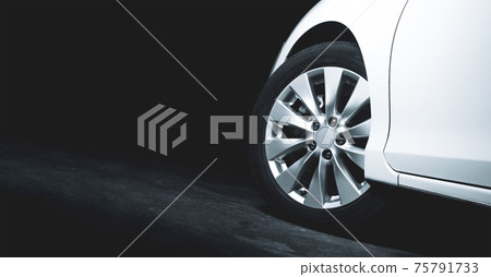 Alloy wheels of the white car are turning on the cement road of parking lot with copy space 75791733