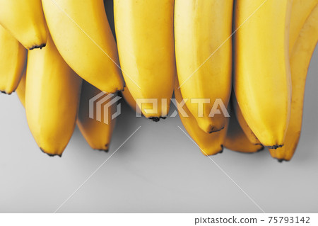A bunch of fresh yellow bananas on a gray background in the fashionable colors of 2021 75793142