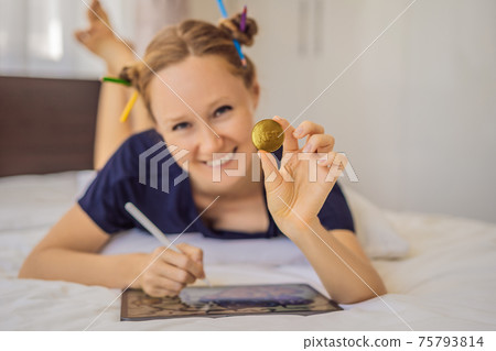 NFT Young woman, a digital artist, creates digital art on a tablet at home and shows a coin with the inscription NTF - non fungible token. Remote work, digital nomad, digital painting, animation 75793814