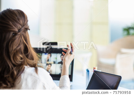 A woman attending an online meeting in her living room A woman attending an online meeting in her living room 75793958