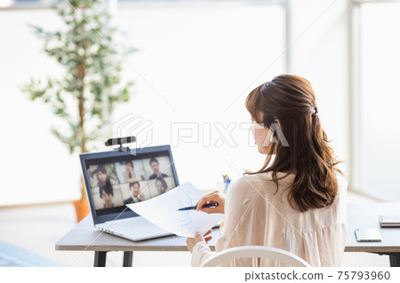 A woman attending an online meeting in her living room 75793960