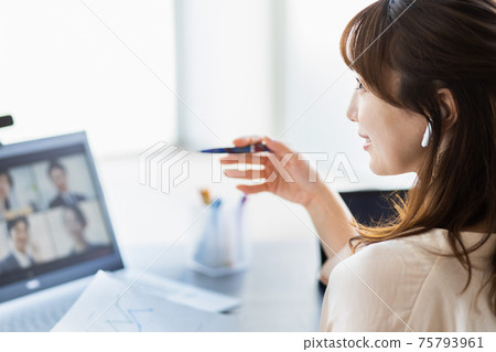 A woman attending an online meeting in her living room 75793961