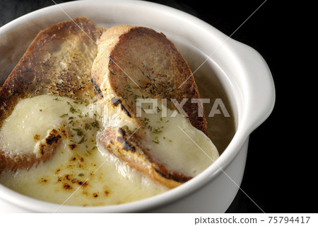 Photographed hot onion soup with charred cheese and French bread on a black background 75794417
