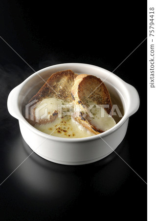 Photographed hot onion soup with charred cheese and French bread on a black background Photographed hot onion soup with charred cheese and French bread on a black background 75794418