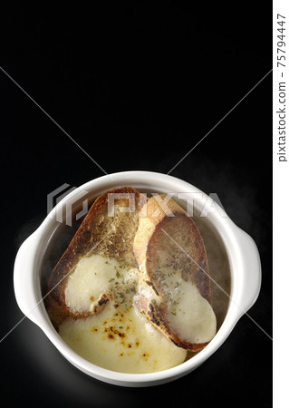 Photographed hot onion soup with charred cheese and French bread on a black background (overhead view) 75794447