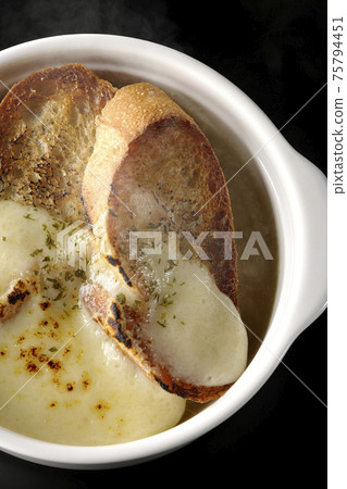 Photographed hot onion soup with charred cheese and French bread on a black background (overhead view) Photographed hot onion soup with charred cheese and French bread on a black background (overhead view) 75794451