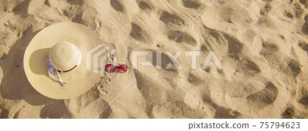 BEACH PARAPHERNALIA ON THE SAND: SUNGLASSES, HAT. TRAVEL TO THE SEA 75794623