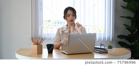 Young businesswoman using laptop computer virtual video conference with her business partner. Young businesswoman using laptop computer virtual video conference with her business partner. 75796996