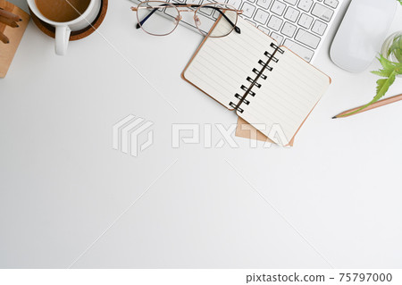 Top view of white office desk with keyboard, coffee cup, glasses, notebook and copy space. 75797000