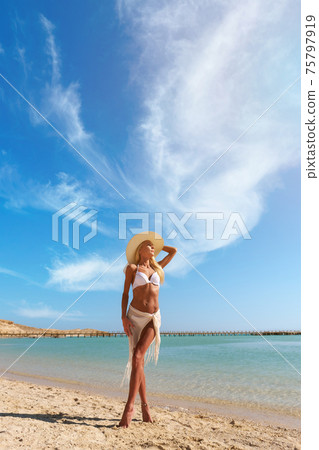 Young fashion woman standing near water on the beach 75797919