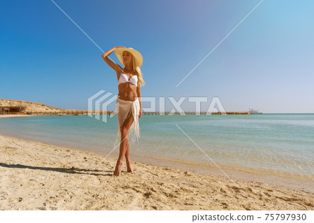 Young fashion woman standing near water on the beach 75797930