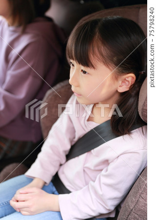 Girl sitting in a junior seat attached to the passenger seat Girl sitting in a junior seat attached to the passenger seat 75798240
