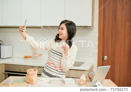 Beautiful woman make photo with fresh raw cake batter on a baking tray, womens hands painted in flour that makes the cake Beautiful woman make photo with fresh raw cake batter on a baking tray, womens hands painted in flour that makes the cake 75798273