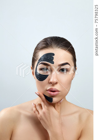 Beauty Face Mask. Skin care face Spa treatment . Beautiful Young Woman with black mask of clay on face. Moisturizer Mask. Beauty Face Mask. Skin care face Spa treatment . Beautiful Young Woman with black mask of clay on face. Moisturizer Mask. 75798325