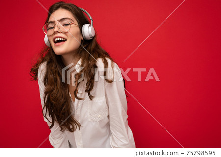 Photo of attractive positive smiling young brunet woman wearing white shirt and optical glasses Photo of attractive positive smiling young brunet woman wearing white shirt and optical glasses 75798595