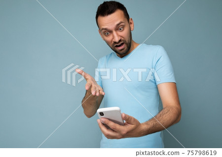 Photo of asking dissatisfied handsome young man with beard wearing everyday blue t-shirt isolated 75798619