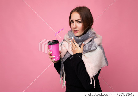 Photo shot of beautiful young brunette woman wearing black sweater and warm scarf isolated over pink 75798643