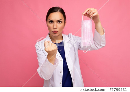 Caucasian woman showing protection face mask isolated on pink background and showing fist Caucasian woman showing protection face mask isolated on pink background and showing fist 75799381