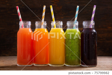bottles of fruit juice on a wooden table 75799982